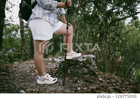 Hiking action on mountain grass trail path. Close up of female hiker shoe. adventurous lifestyle of hiker and backpack to travel and trek mountain, enjoy every walk and hike part of thrilling journey 128775850
