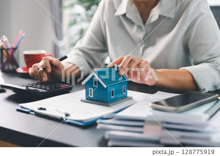 Real estate agent agree to buy home to clients agency office. House model, real estate agent, customer discussing for contract to buy house, insurance, loan real estate background. Concept agreement. Real estate agent agree to buy home to clients agency office. House model, real estate agent, customer discussing for contract to buy house, insurance, loan real estate background. Concept agreement. 128775919