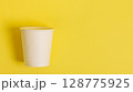 Disposable paper cup for coffee and tea on a bright orange background. 128775925