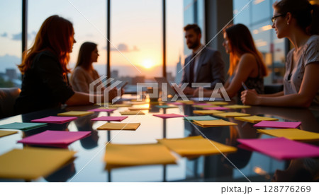 Creative brainstorming session with colorful sticky notes on table, sunset view through large windows, team collaboration 128776269