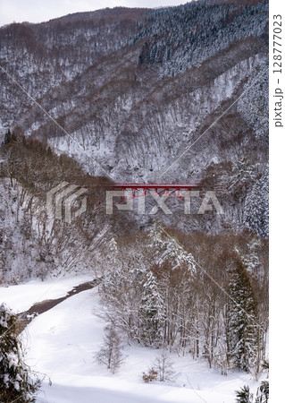 雪景色に映える赤い高井橋と山田温泉周辺の冬の渓谷風景（長野県） 128777023