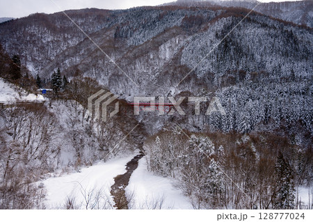 雪景色に映える赤い高井橋と山田温泉周辺の冬の渓谷風景（長野県） 128777024