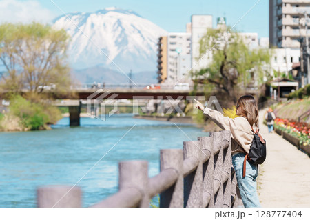 Woman tourist sightseeing Iwate mountain and Kitakami river with flowers in Spring, happy traveler travel in Morioka city, Iwate prefecture, Japan. famous Landmark Travel and Vacation destination 128777404
