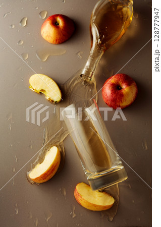 Apple juice is poured into a glass. Apple juice is poured into a glass. 128777947