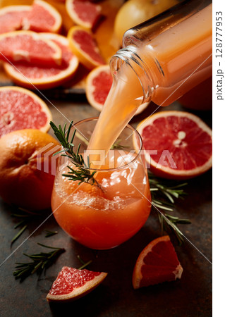 Grapefruit juice is poured into a glass. 128777953