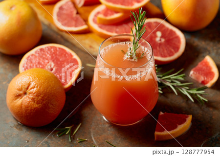 A glass of grapefruit juice garnished with a rosemary sprig. A glass of grapefruit juice garnished with a rosemary sprig. 128777954