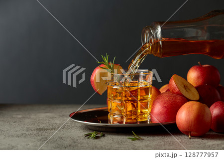 Apple kombucha is poured from a bottle into a glass. 128777957