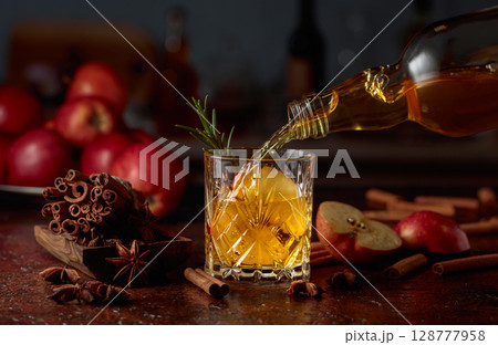 Apple kombucha is poured from a bottle into a crystal glass. Apple kombucha is poured from a bottle into a crystal glass. 128777958