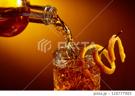Whiskey or bourbon pouring into a crystal glass. 128777985