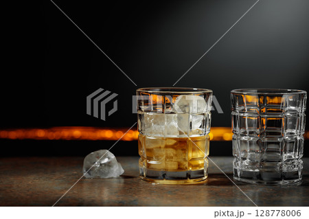 Whiskey with ice on a dark background. 128778006