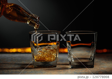 Whiskey is poured into a crystal glass. 128778008