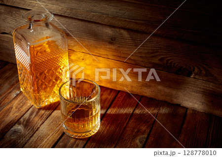 Elegant whiskey glass and decanter on a old wooden table. 128778010