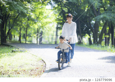 自転車に乗る練習をする親子 128779096