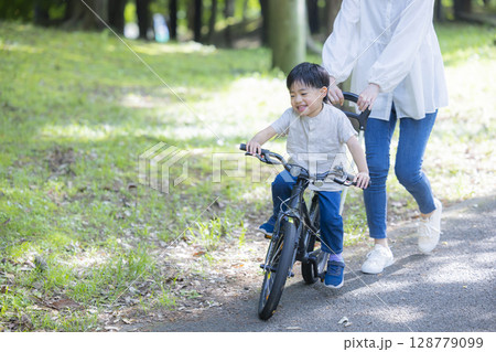 自転車に乗る練習をする親子 128779099