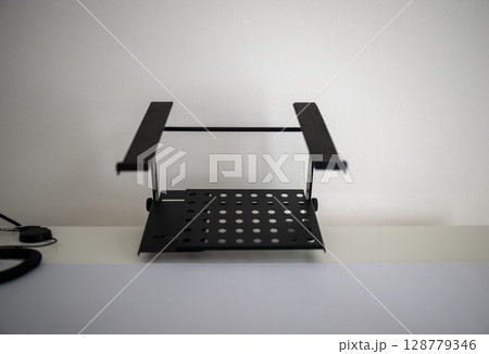 Adjustable metal laptop stand on white desk in minimal home office Adjustable metal laptop stand on white desk in minimal home office 128779346