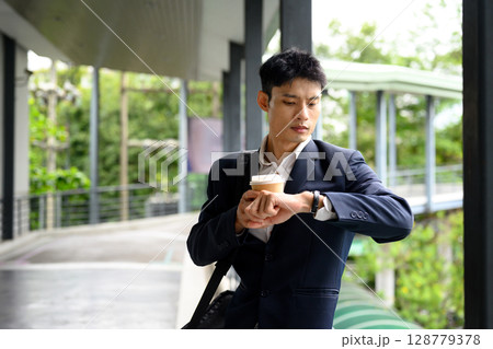 Businessman rushing to meeting, holding takeaway coffee and checking the time 128779378
