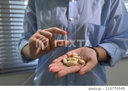 Person holding white tablets in hand, highlighting daily supplement or medication routine Person holding white tablets in hand, highlighting daily supplement or medication routine 128779549