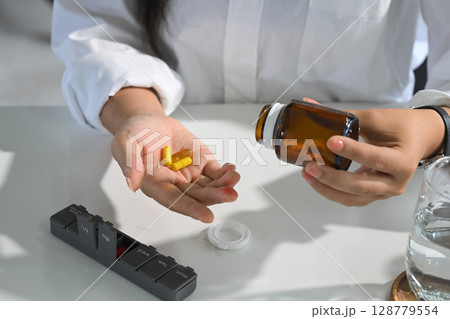 Hand holding vitamin supplements, ready for daily dosage. Wellness concept 128779554