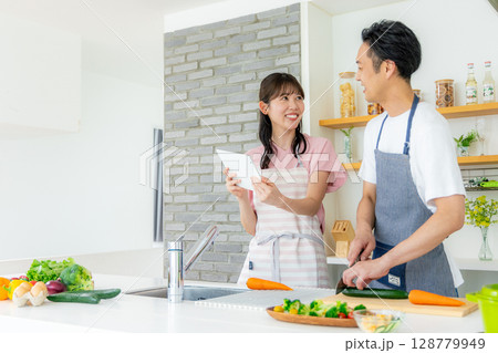 タブレットでレシピを確認しながら料理をする男女夫婦 タブレットでレシピを確認しながら料理をする男女夫婦 128779949
