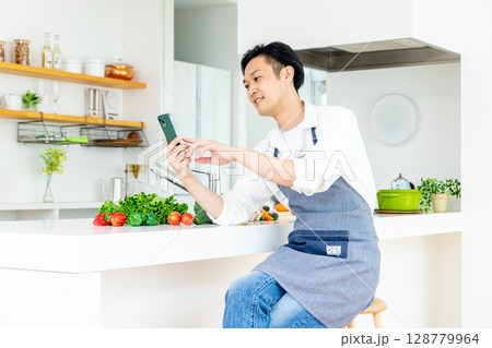 キッチンでスマホを使う男性 128779964