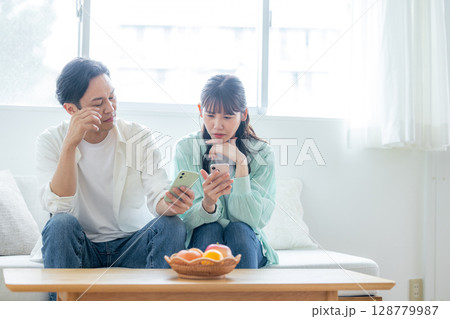 スマホを見て落ち込む夫婦 128779987
