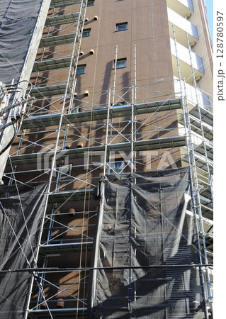 大規模改修工事の足場 組み上げれていく工事現場の足場 マンションの大規模修繕工事 大規模改修工事の足場 組み上げれていく工事現場の足場 マンションの大規模修繕工事 128780597