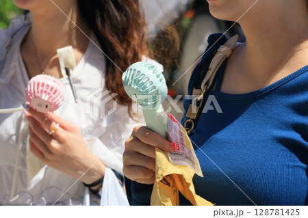 ハンディファンを持って歩く女性 128781425