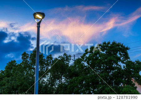 茜雲浮かぶ夕焼け空を背景にわびしく灯る公園の街灯　奈良市街地の公園にて 128781990