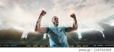 Bearded football player raising fists in triumph in modern 3D stadium 128782009