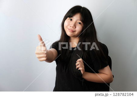 Asian girl in black t-shirt carrying backpack Giving Thumbs Up 128782104