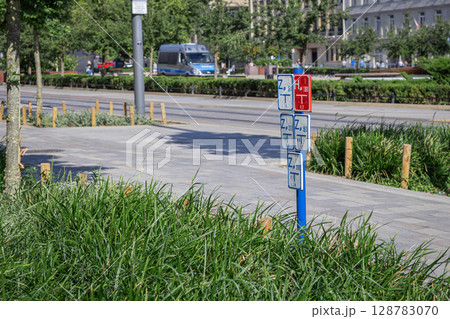 Multiple white and red utility signs displaying technical codes and measurements on a blue pole, crucial for urban infrastructure planning and public service management in a city 128783070