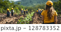 a woman leading a tree-planting initiative in a rural area, showing a group of volunteers where to plant saplings, with a natural environment and clear copy space on the right 128783352