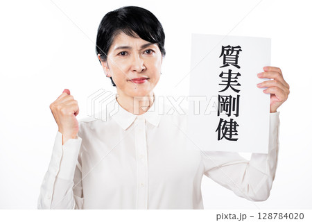 質実剛健と書かれた紙を持ちガッツポーズでやる気をみせるシニア女性 128784020