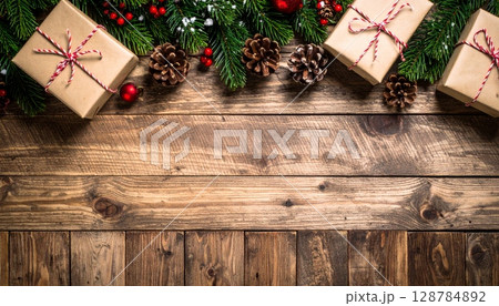 Christmas decorations and pine tree branches on a rustic wooden background with natural texture, perfect for holiday celebrations Christmas decorations and pine tree branches on a rustic wooden background with natural texture, perfect for holiday celebrations 128784892