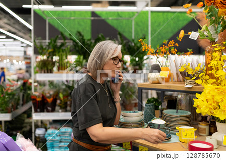 Mature woman engaged in shopping for home and garden products in a large retail store Mature woman engaged in shopping for home and garden products in a large retail store 128785670