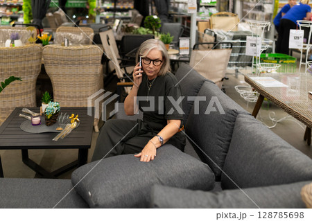 Middle-aged woman shopping in a home improvement store exploring furniture and home d cor Middle-aged woman shopping in a home improvement store exploring furniture and home d cor 128785698