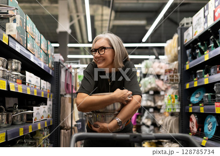 Middle-aged woman enjoys shopping experience in a home improvement store while exploring various Middle-aged woman enjoys shopping experience in a home improvement store while exploring various 128785734