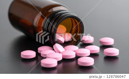 Isolated red and white pills and capsules spill from a bottle, symbolizing pharmaceutical care and medical treatment options for health 128786047