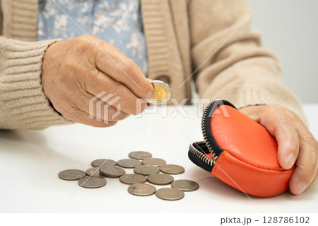Asian  elderly woman holding counting coin money in purse. Poverty, saving problem in retirement. 128786102