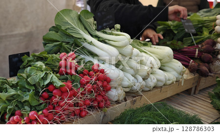 Vibrant farmers market bursting with fresh vegetables showcasing colorful radishes and crisp greens in a lively outdoor setting 128786303