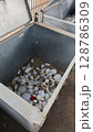 Old and discarded light bulbs collected in a large storage box at a recycling center during the afternoon sunlight 128786309