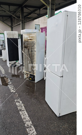 Discarded refrigerators awaiting recycling at an electronic waste facility on a rainy day in the city 128786310