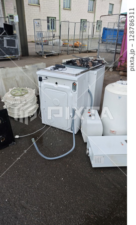 Discarded appliances awaiting recycling at an industrial site during daylight hours close to urban surroundings 128786311