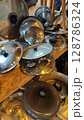 Piled collection of gleaming pot lids in a cozy workshop capturing the essence of culinary creativity and home cooking heritage 128786324
