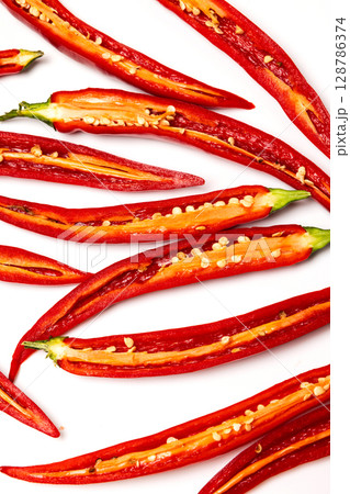 Sliced pods of red natural organic chili pepper on white background Sliced pods of red natural organic chili pepper on white background 128786374