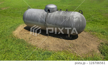 Large industrial propane tank installed outdoors on grass, designed for fuel storage and efficiency. The tank showcases durability and purpose for various industries and homes Large industrial propane tank installed outdoors on grass, designed for fuel storage and efficiency. The tank showcases durability and purpose for various industries and homes 128786561