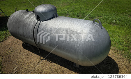 Large industrial propane tank installed outdoors on grass, designed for fuel storage and efficiency. The tank showcases durability and purpose for various industries and homes 128786564