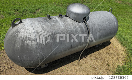 Large industrial propane tank installed outdoors on grass, designed for fuel storage and efficiency. The tank showcases durability and purpose for various industries and homes Large industrial propane tank installed outdoors on grass, designed for fuel storage and efficiency. The tank showcases durability and purpose for various industries and homes 128786565
