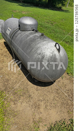 Large industrial propane tank installed outdoors on grass, designed for fuel storage and efficiency. The tank showcases durability and purpose for various industries and homes Large industrial propane tank installed outdoors on grass, designed for fuel storage and efficiency. The tank showcases durability and purpose for various industries and homes 128786568