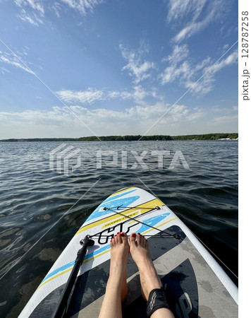 The legs of a girl riding a paddleboard in the summer. High quality photo 128787258